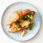 Croissant gevuld met roerei, gerookte zalm en veldsla