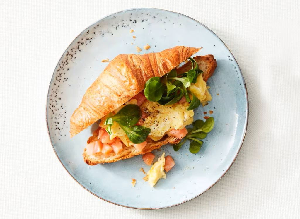 croissant gevuld met roerei, gerookte zalm en veldsla