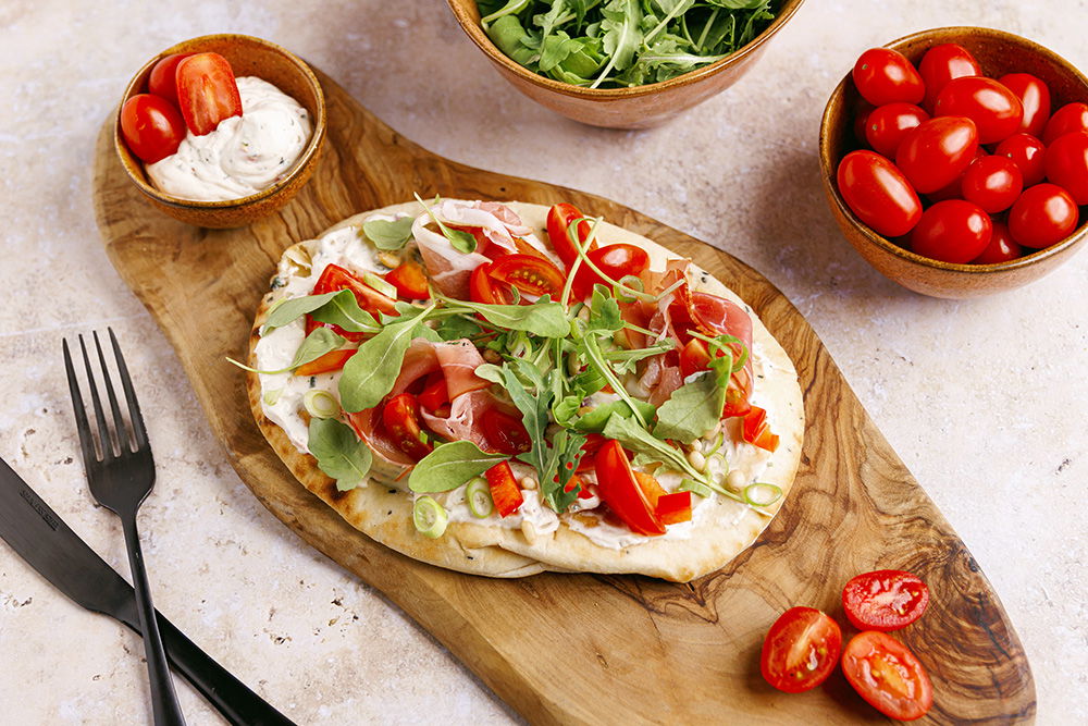 Naambrood met roomkaasspread tomaat en rauwe ham