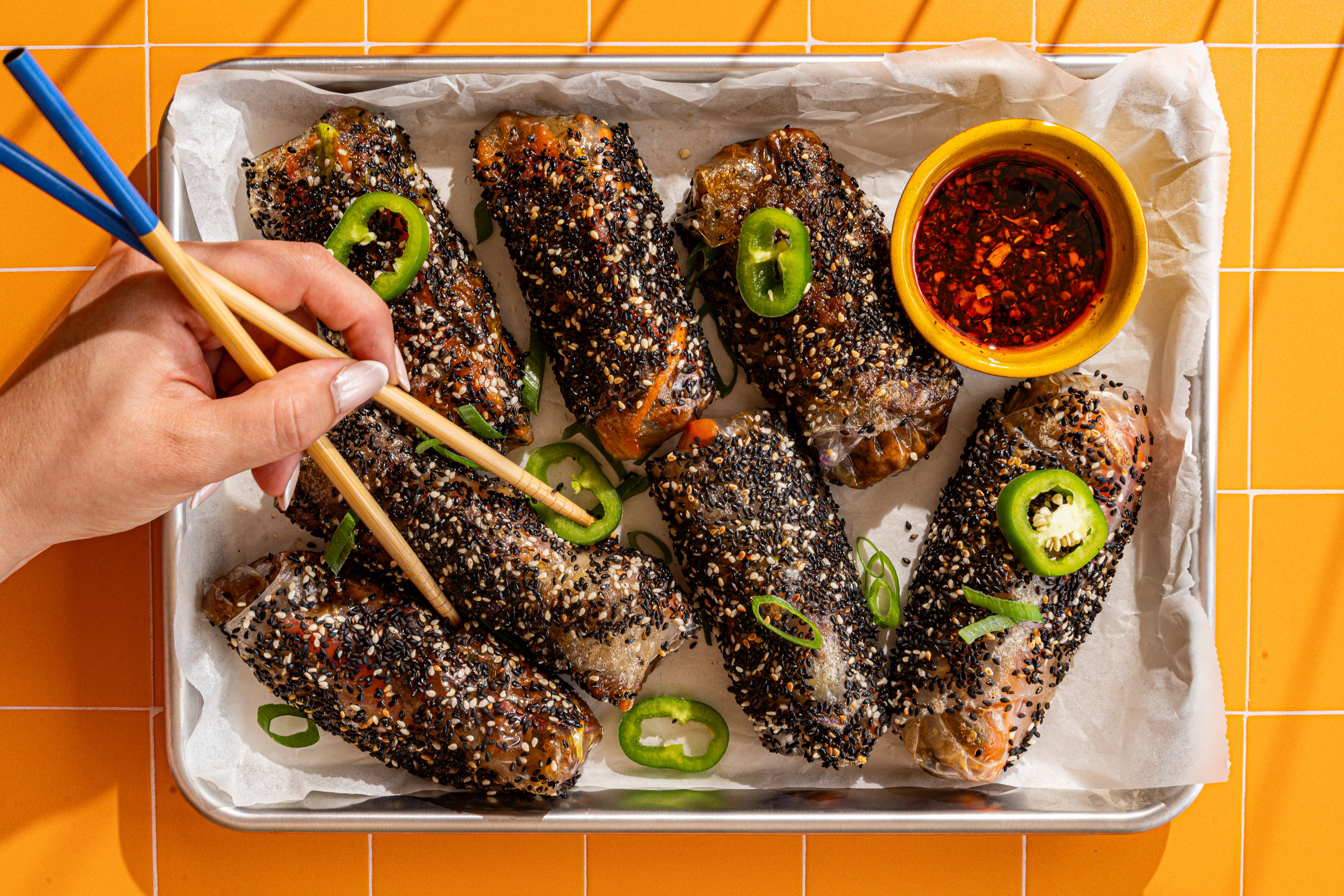 Krokante Thaise beef rolletjes met sesamzaadjes en pittige sojadip op een serveerschaal