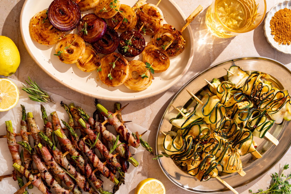 Drie verschillende barbecuegroenten: miso courgettespiesjes, gekaramelliseerde uienstokjes en groene asperges met krokante bacon.