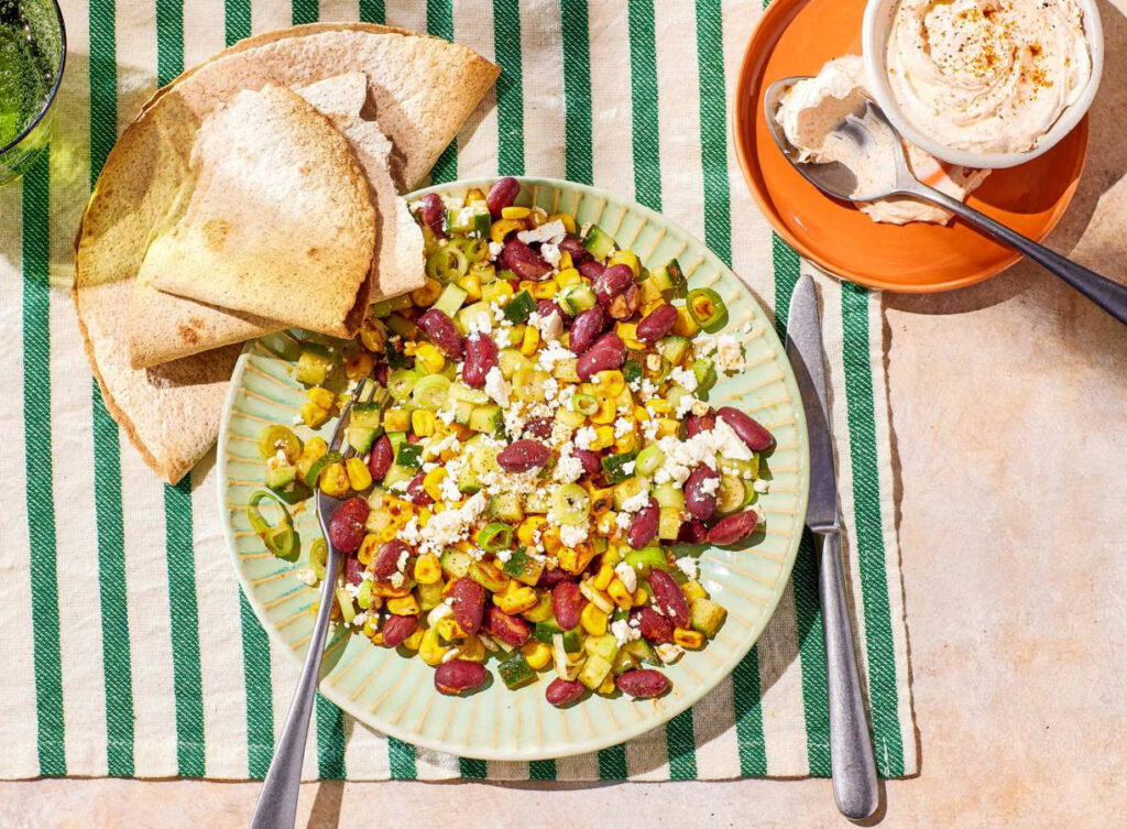 Crispy maissalade met gegrilde maïs, witte kaas, kidneybonen, komkommer, bosui en tortilla’s.