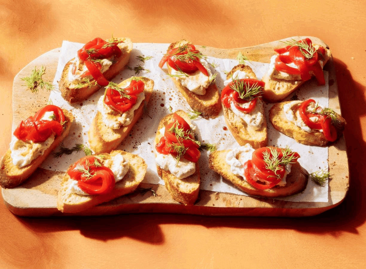 Crostini met ricotta, gegrilde paprika, dille en balsamico op een serveerschaal.
