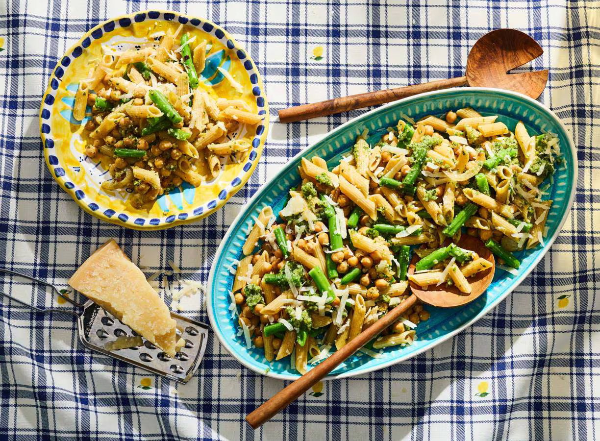 Pastasalade met pesto, kikkererwten, sperziebonen en geraspte Grana Padano in een schaal.