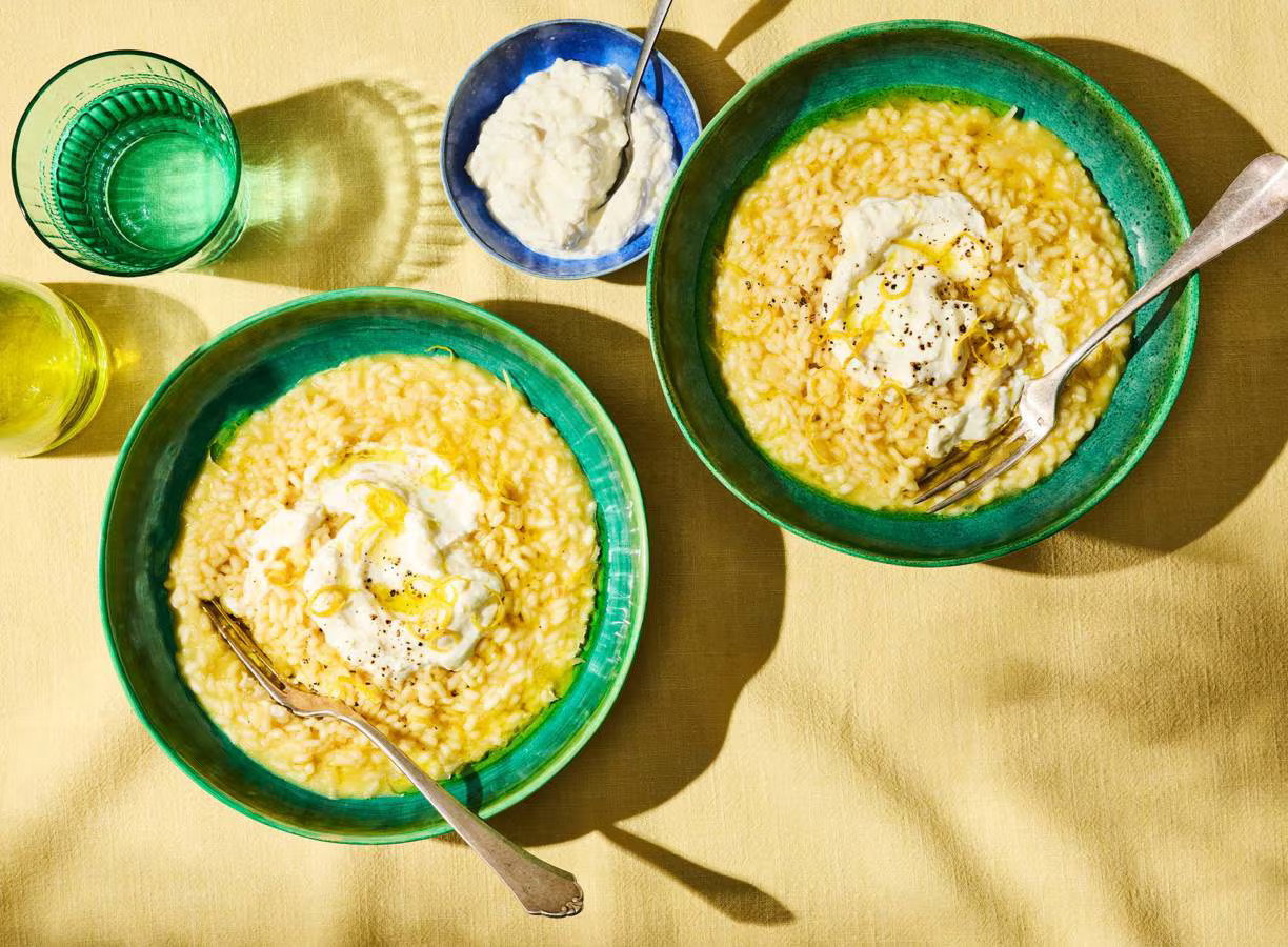Romige risotto al limone met citroenrasp, buffelricotta en Parmigiano Reggiano op een bord.