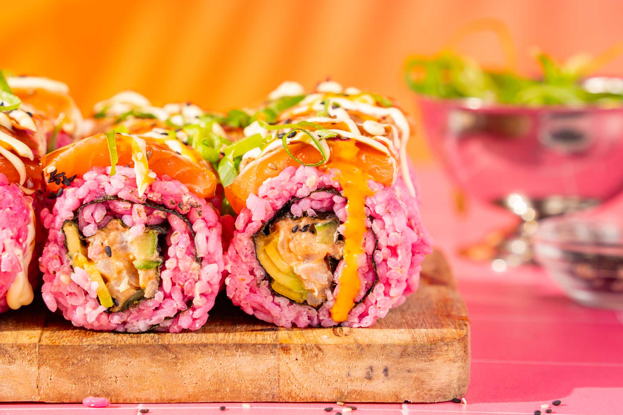 Flamed spicy pink sushi met roze sushirijst, spicy tonijn, avocado, komkommer, mango en geflambeerde zalm.