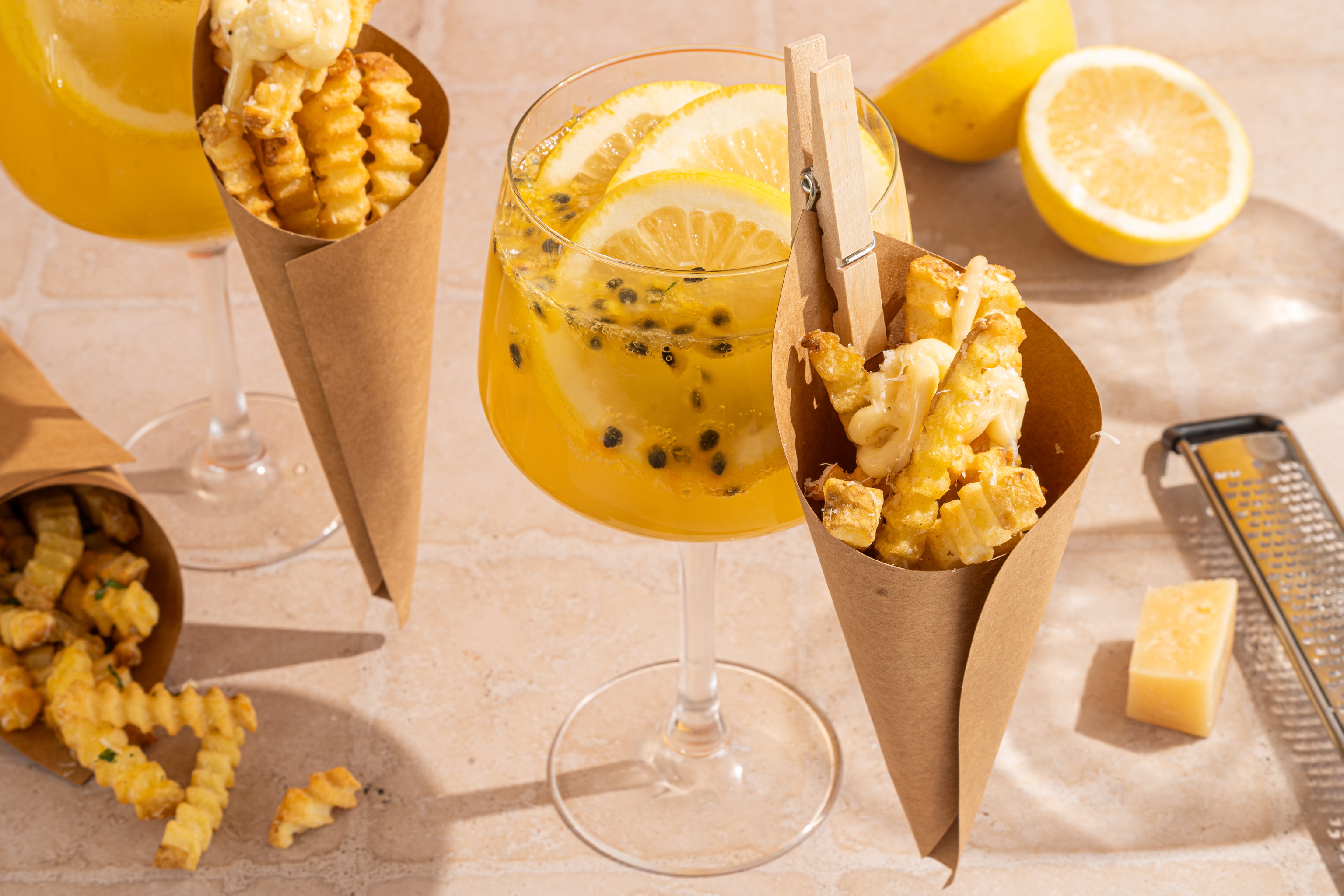 Sweet summer spritz met grapefruit, prosecco en passievrucht geserveerd met Parmezaanse frietjes en truffelmayonaise.
