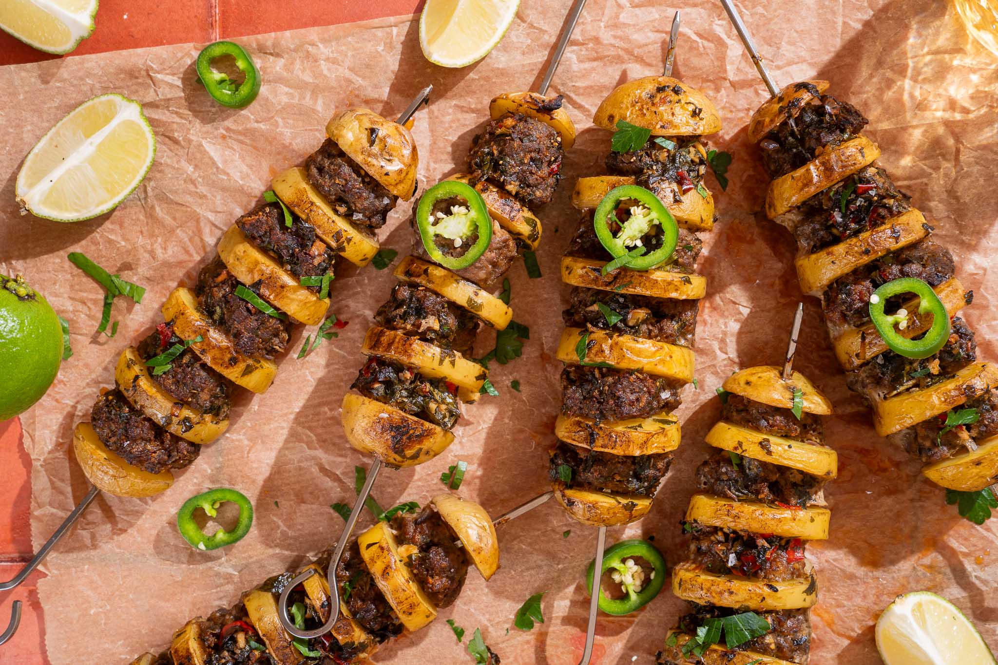 Aardappel-gehaktspiesjes met chimichurriboter, jalapeño, verse peterselie en limoen.