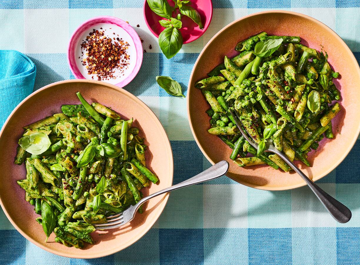 Twee kommen met green goddess-pasta met sperziebonen en basilicum.