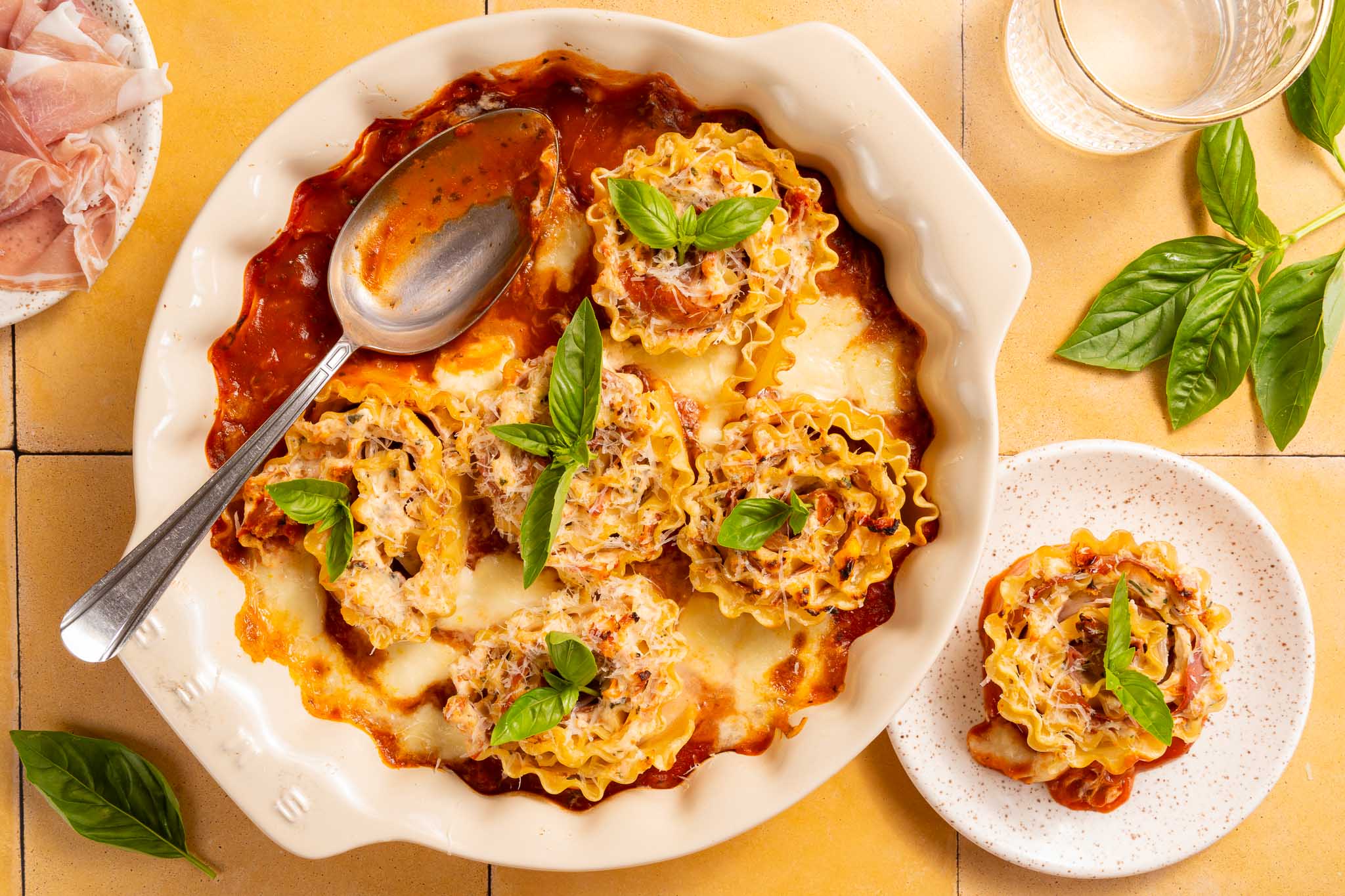 Lasagnerolletjes met ricotta, prosciutto, zongedroogde tomaat en mozzarella in een kruidige tomatensaus.