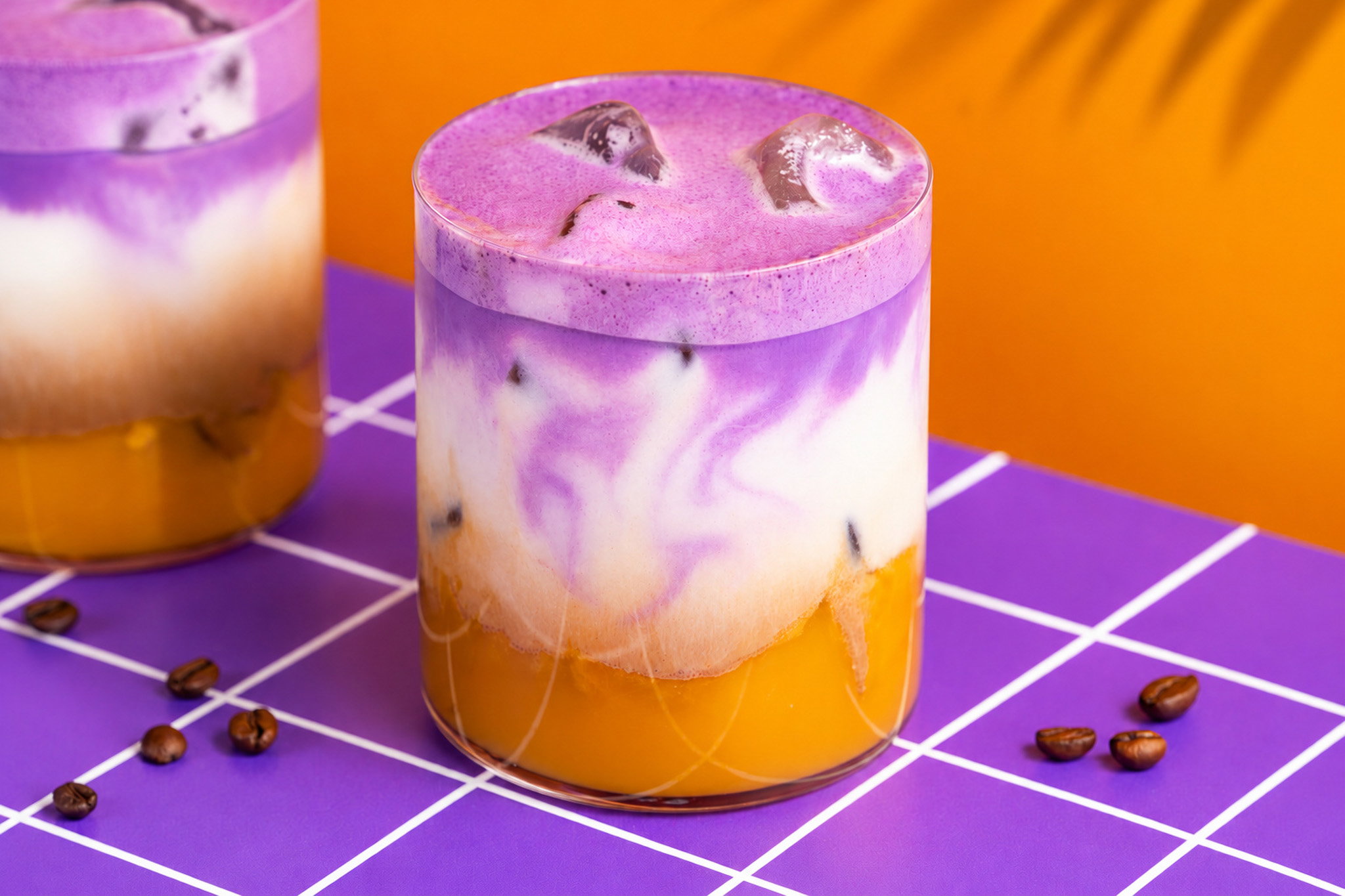 Mango ube iced latte met mangopuree, kokosmelk, espresso en paarse ube foam.