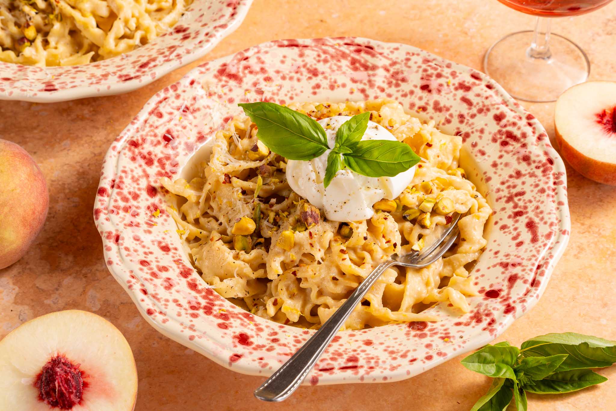 Perzik burrata pasta met romige perziksaus, mini burrata, pistachenoten, Parmezaanse kaas, basilicum en citroen.