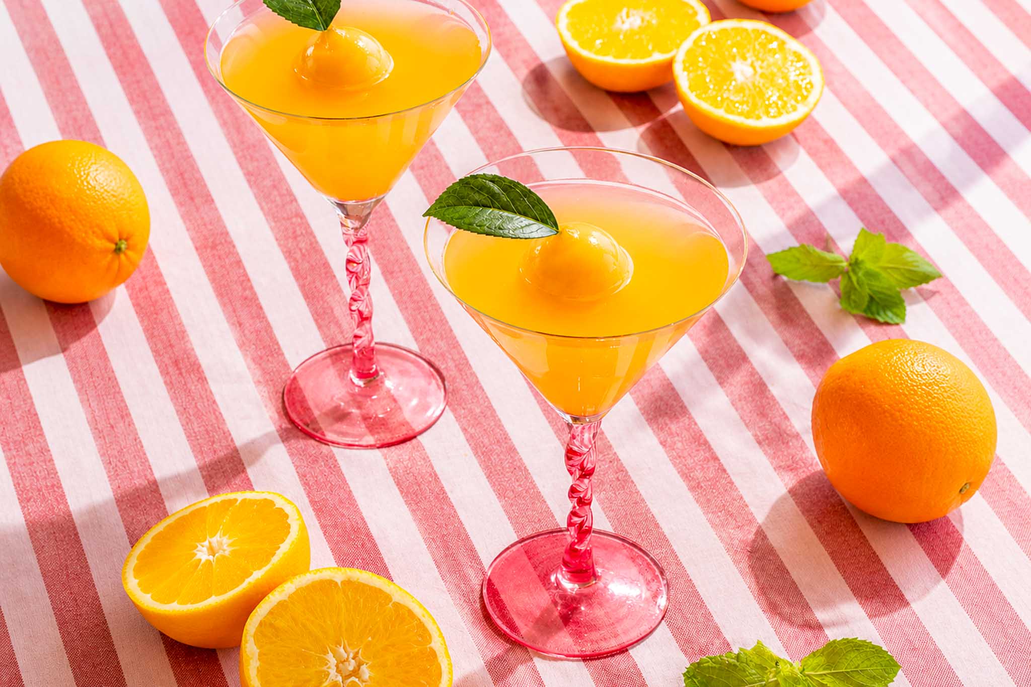 Summer mimosa’s met prosecco, sinaasappellikeur en grote ijsbollen van vers sinaasappelsap en munt.