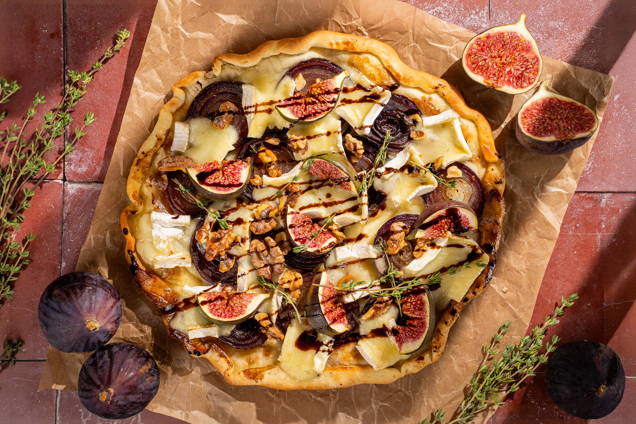 Upside-downpizza met gekaramelliseerde rode ui, brie, verse vijgen, pecannoten, balsamico en tijm.