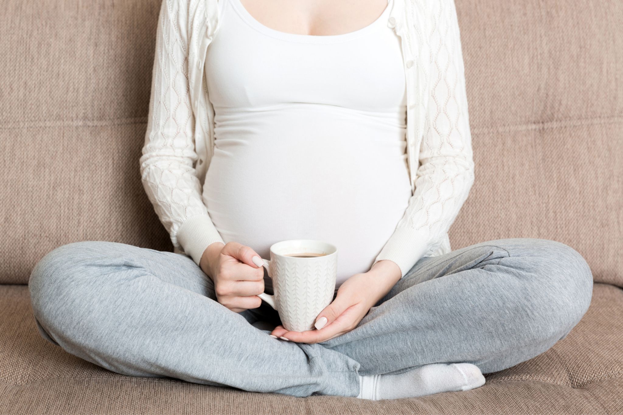 Zwangere vrouw drinkt koffie op bank