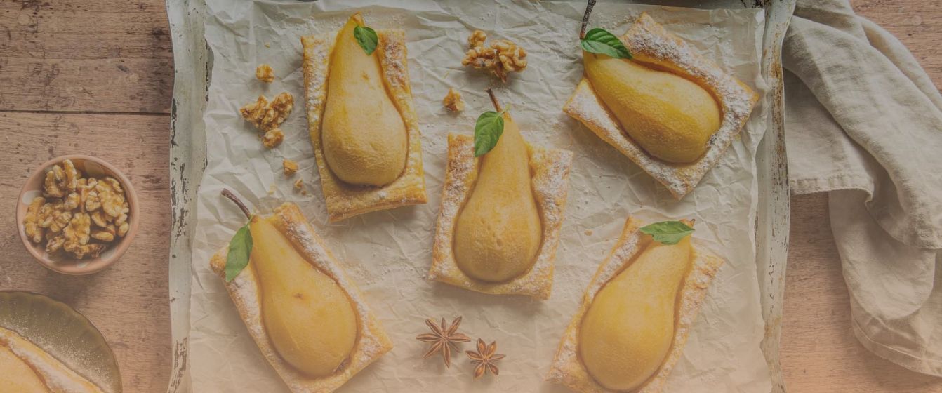 Bladerdeeghapjes met peer op een bakplaat