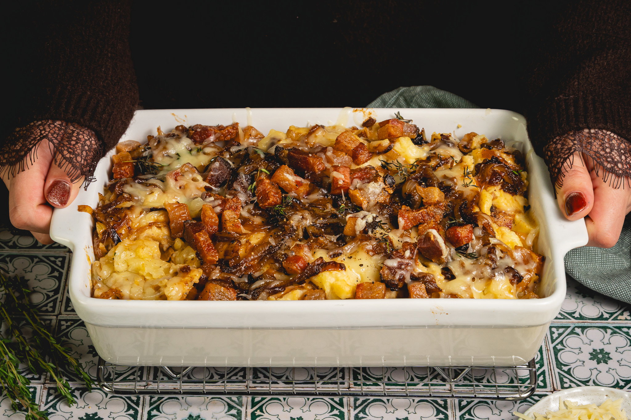 Franse uiensoep stamppot met gekaramelliseerde uien, gesmolten gruyère, krokante guanciale en verse tijm in een ovenschaal.